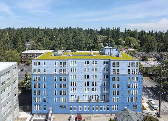 A large blue building with a green roof is surrounded by trees.