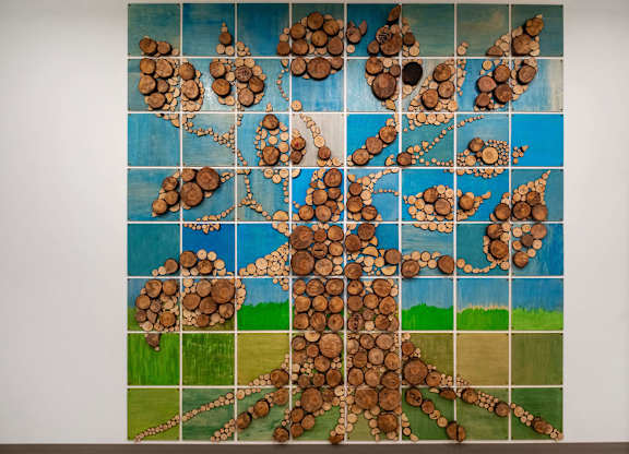 A painting of a tree made out of wood slices.