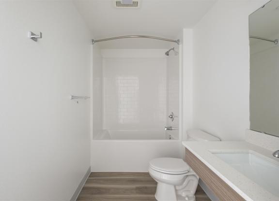 A white bathroom with a toilet, sink, and bathtub at Nook at Northaven Apartments, Seattle
