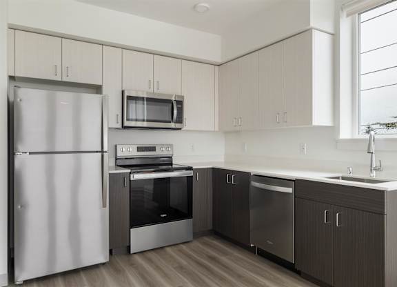 A modern kitchen with a refrigerator, microwave, oven, and sink at Nook at Northaven Apartments, Seattle, 98125
