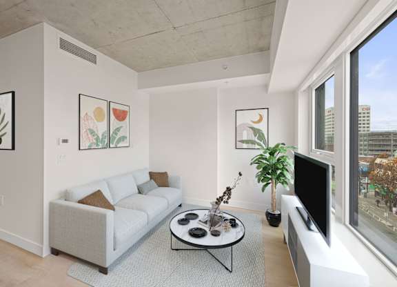 A living room with a white couch, a coffee table, and a flat screen TV.