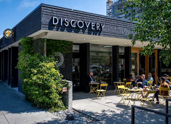 A group of people are sitting outside of a coffee shop.