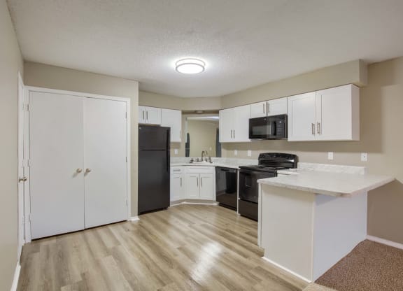 a kitchen with white cabinets and black appliances