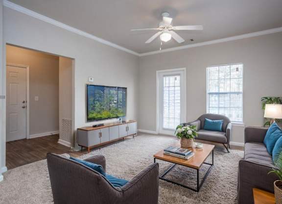 A living room with a brown chair, a grey couch, a coffee table, and a television.
