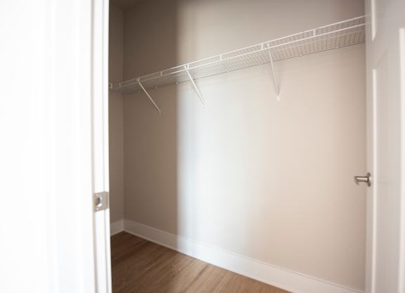 A white closet with a door and a shelf.