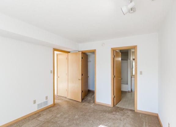 an empty room with a ceiling fan and a kitchen in the background