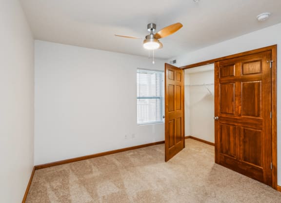 an empty bedroom with a closet and a ceiling fan