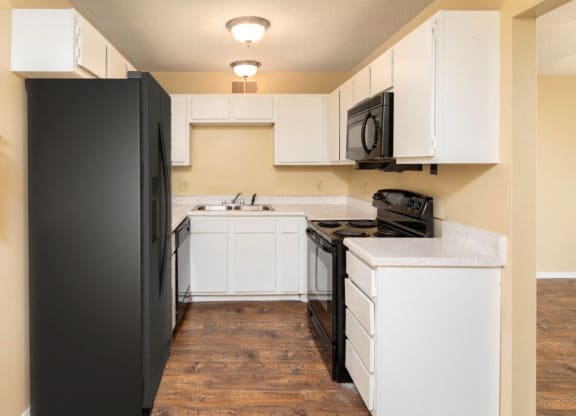 a kitchen with white cabinets and a black refrigerator