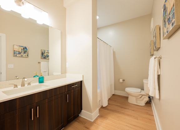 A bathroom with a white sink and brown cabinets.