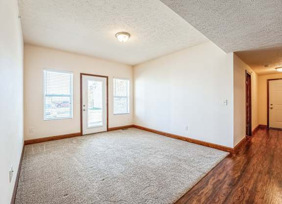 the living room and dining room of an empty house with wood floor and white walls