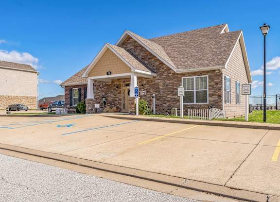 the front of a brick house with a driveway and a parking lot