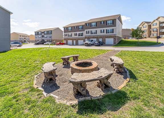 a fire pit with wooden benches in front of an apartment building