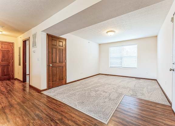the living room and entryway of a house with wood flooring and white walls