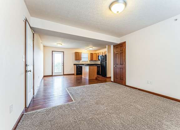 an empty living room and kitchen with wood floors and white walls