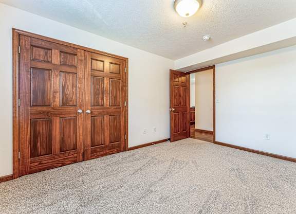 an empty living room with wood doors and carpet