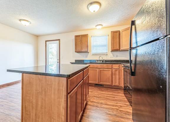 a kitchen with wooden cabinets and a black counter top