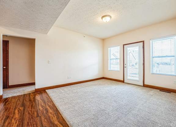 the living room of an empty home with wood flooring and white walls