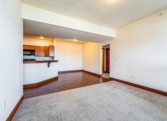 an empty living room with hard wood flooring and a kitchen