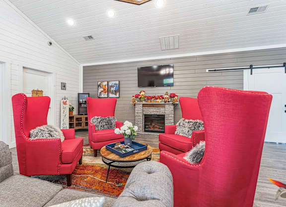 a living room with red chairs and a fireplace