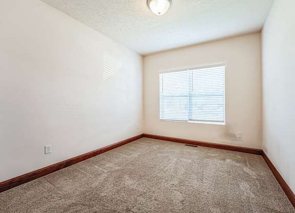 an empty room with carpet and a window