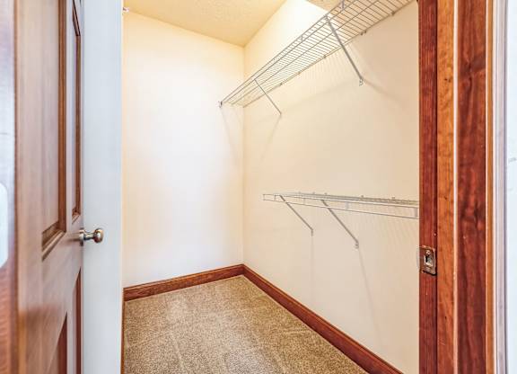a walk in closet with a wood door and a white wall with a hanging rack