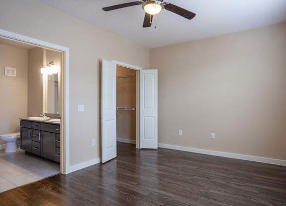 A room with a ceiling fan and a cabinet with a mirror.
