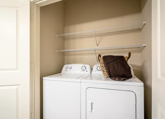 an empty laundry room with a washer and dryer and a basket on top