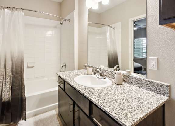 A bathroom with a sink, mirror, and shower.