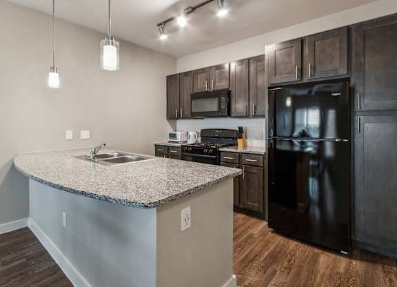 A kitchen with a granite countertop and black appliances.