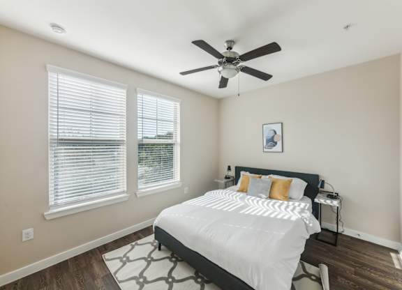 A bedroom with a bed, a ceiling fan, and a window with blinds.