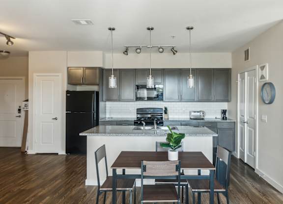 A kitchen with a table and chairs in front of it.