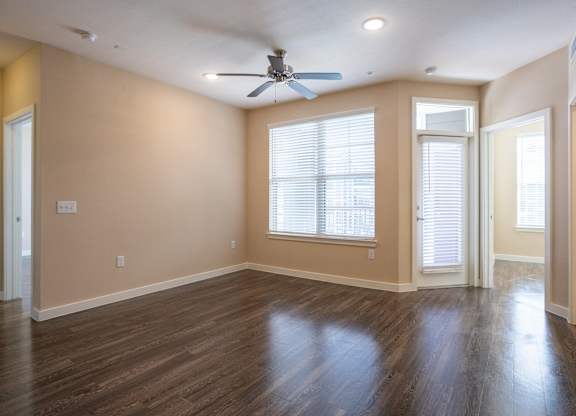 an empty living room with wood floors and a ceiling fan