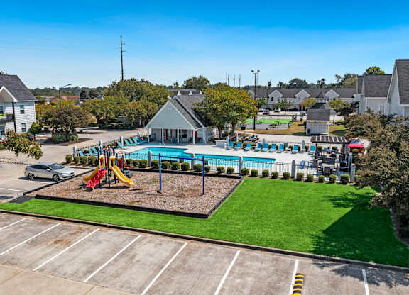 A playground with a slide and swimming pool in the middle of a parking lot.