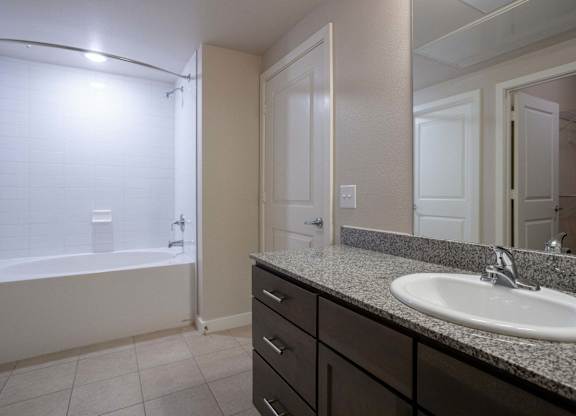 A bathroom with a sink, mirror, and bathtub.