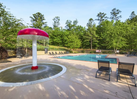 a fountain with a red umbrella next to a pool