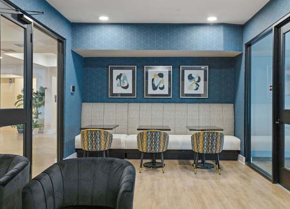 A room with a blue wall and a bench with three chairs.