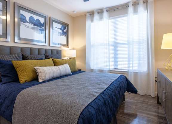 A bedroom with a bed, pillows, and a lamp.