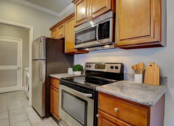 A kitchen with a stove, refrigerator, and microwave.