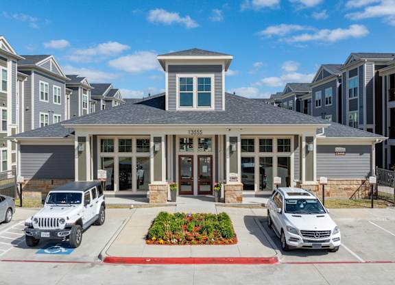 an apartment building with two cars parked in front of it