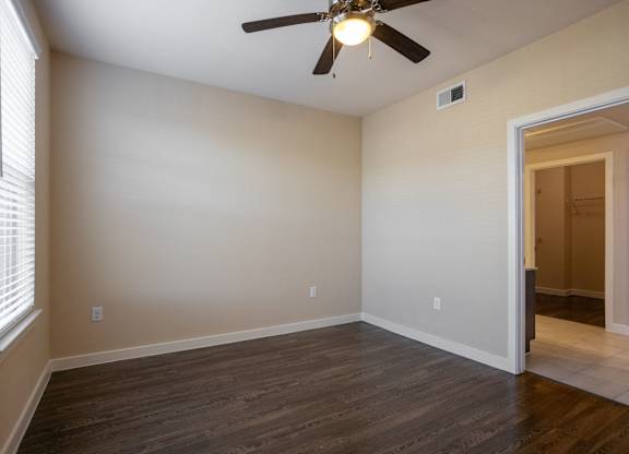 an empty living room with wood floors and a ceiling fan
