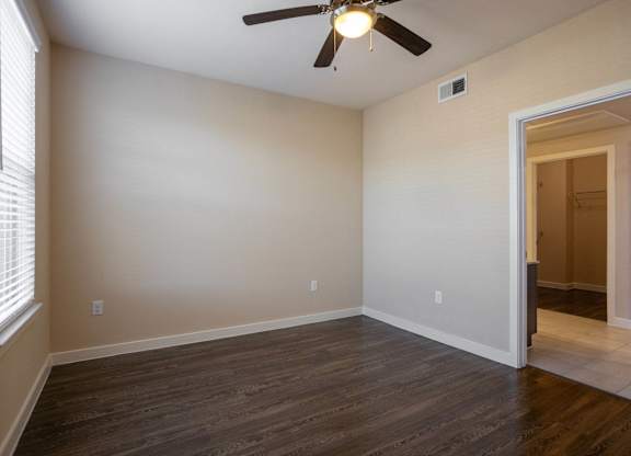 A room with a ceiling fan and wooden flooring.