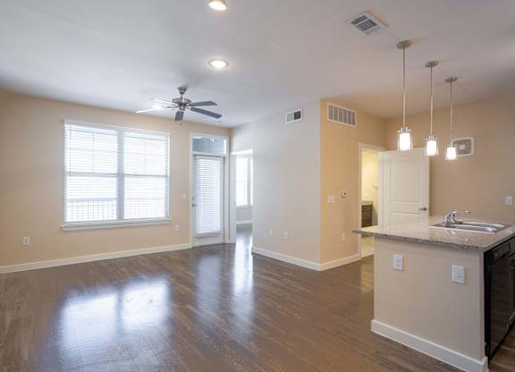 A spacious room with a kitchen area and a ceiling fan.