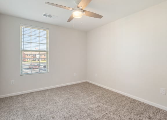 an empty room with a ceiling fan and a window