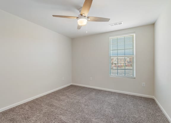an empty room with a ceiling fan and a window