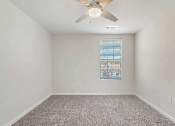 an empty room with a ceiling fan and a window