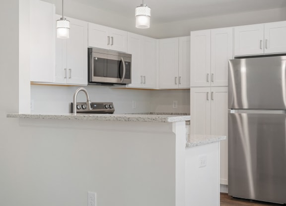an empty kitchen with white cabinets and a stainless steel refrigerator