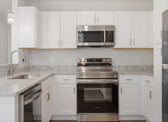a kitchen with white cabinets and stainless steel appliances