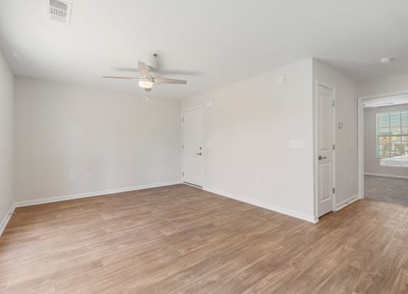 an empty living room with wood flooring and a ceiling fan