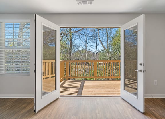 an open door leading to a balcony with a view of the woods