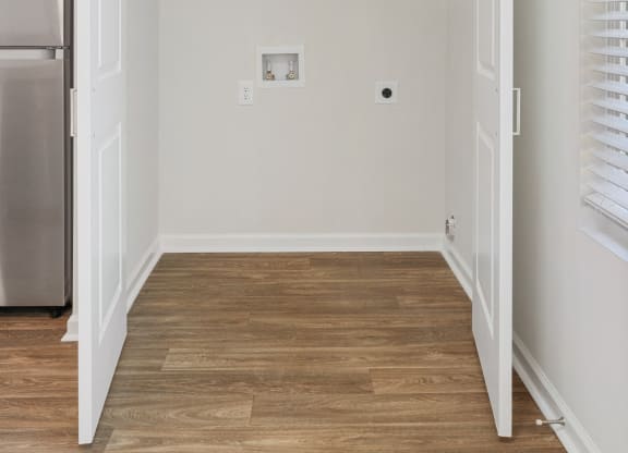 an empty room with white walls and wood floors and a refrigerator